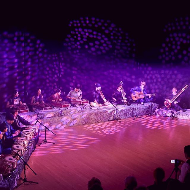 Large Indian classical ensemble with purple stage lighting